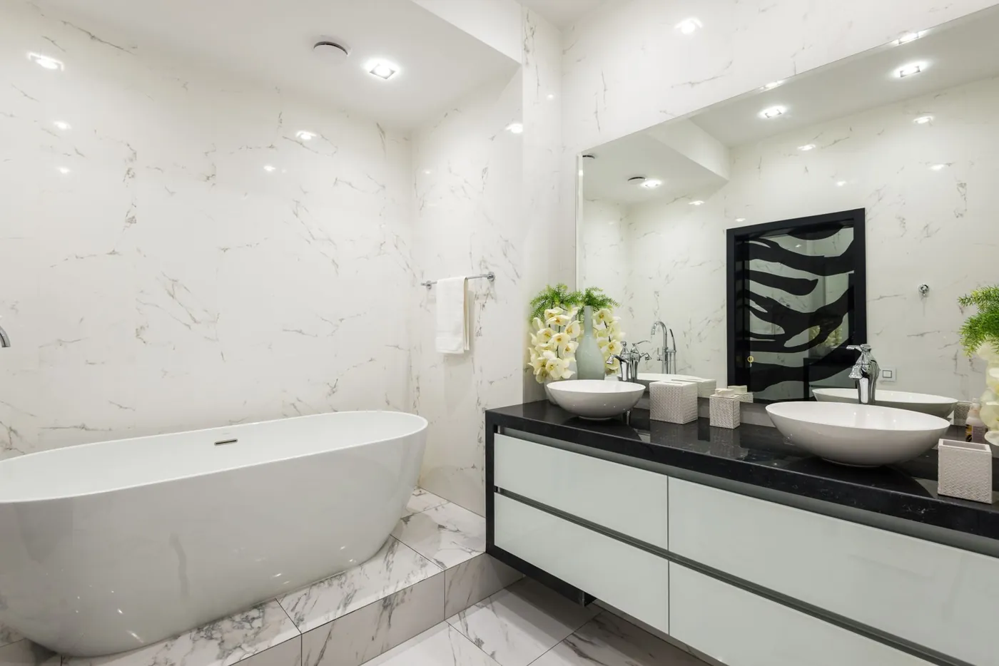 Witte badkamer met ligbad, marmer en wastafelmeubel